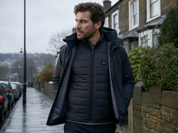 Person wearing a black heated gilet under a light jacket on a cold British morning